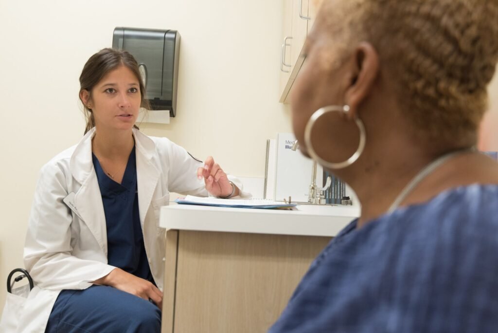 Médico oncólogo conversando con un paciente en un consultorio, revisando documentación clínica