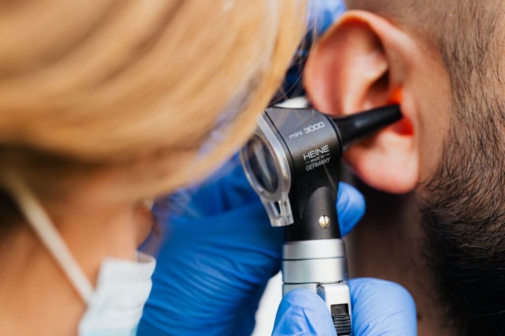 Otorrinolaringólogo examinando el oído de un paciente durante una consulta médica