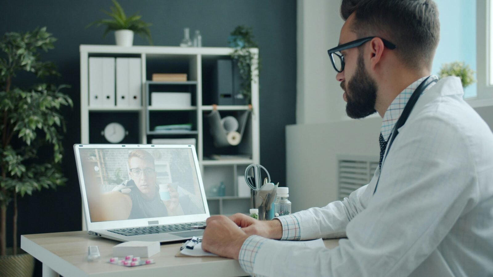 Persona adulta hablando por videollamada con un médico desde su hogar, con una notebook sobre la mesa