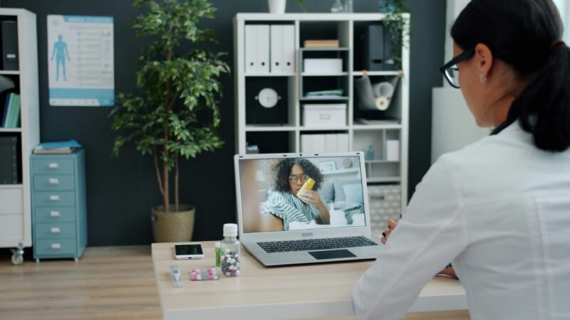 Médico clínico conversando con un paciente adulto en un consultorio luminoso