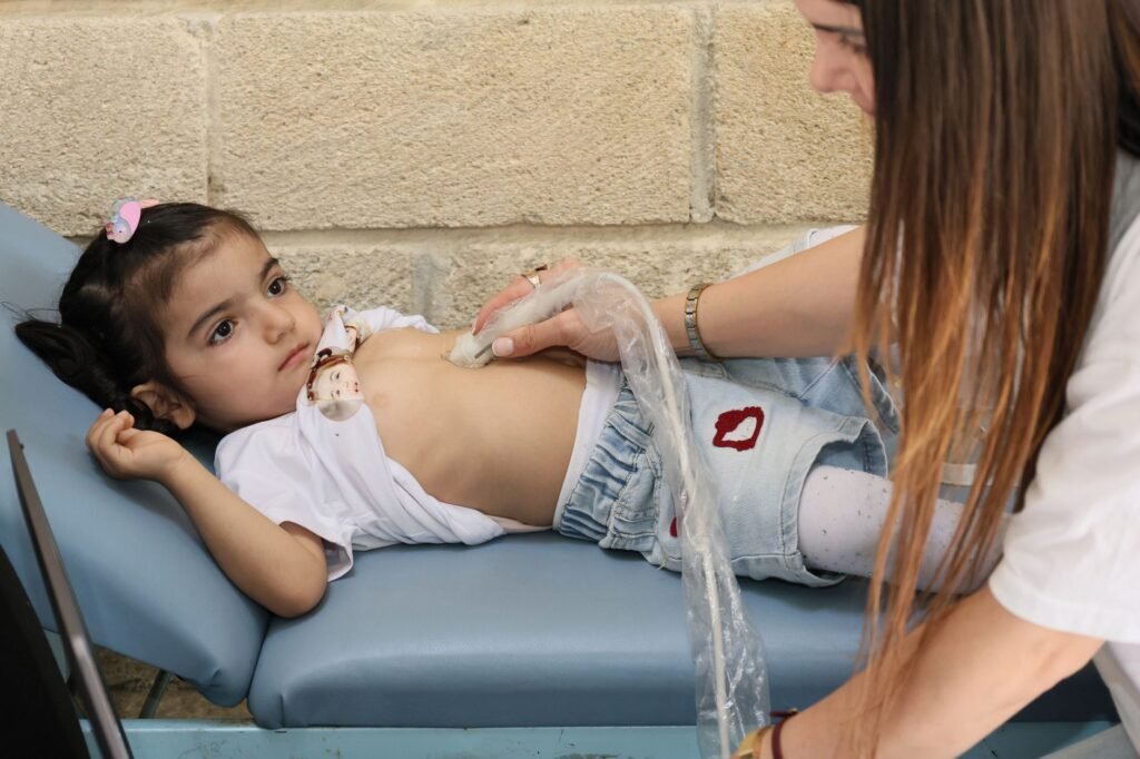 Médica especialista en gastroenterología infantil examinando el abdomen de un niño pequeño en un consultorio pediátrico