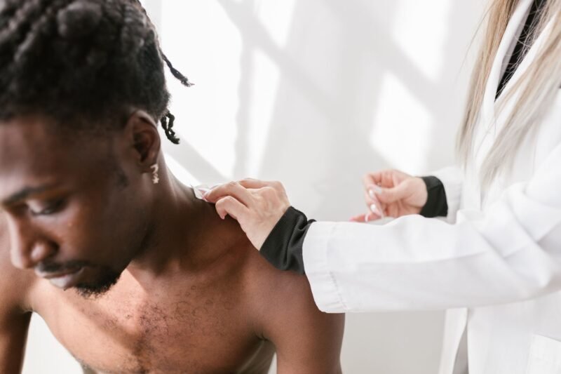 Dermatólogo examinando la piel de un paciente adulto con dermatoscopio en consultorio